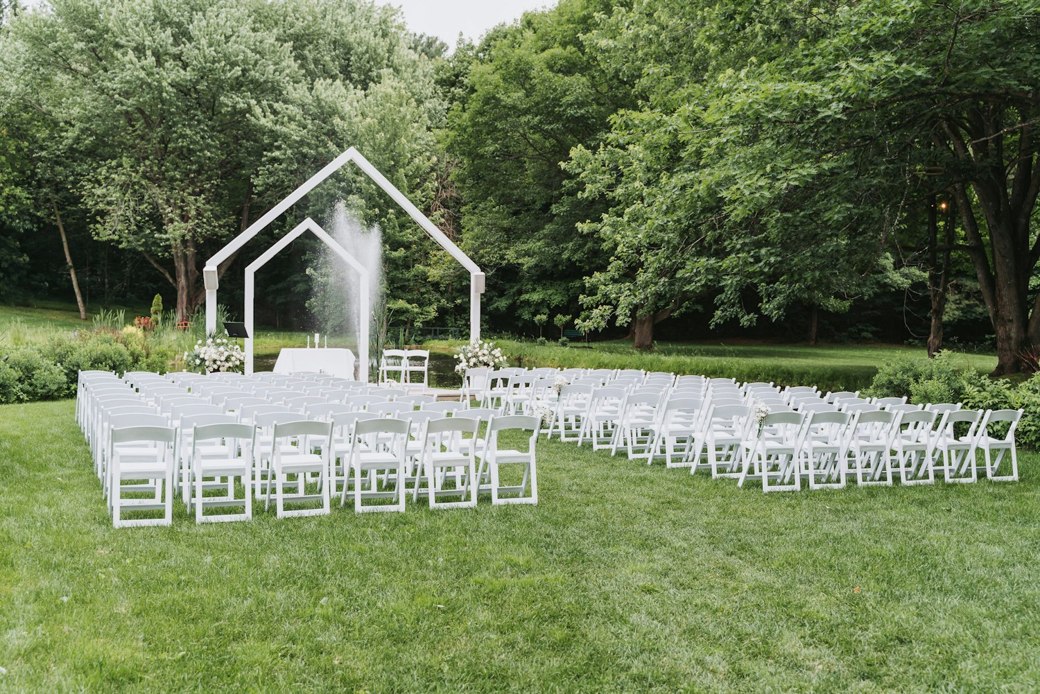 White chairs set for an outdoor ceremony on the lawn