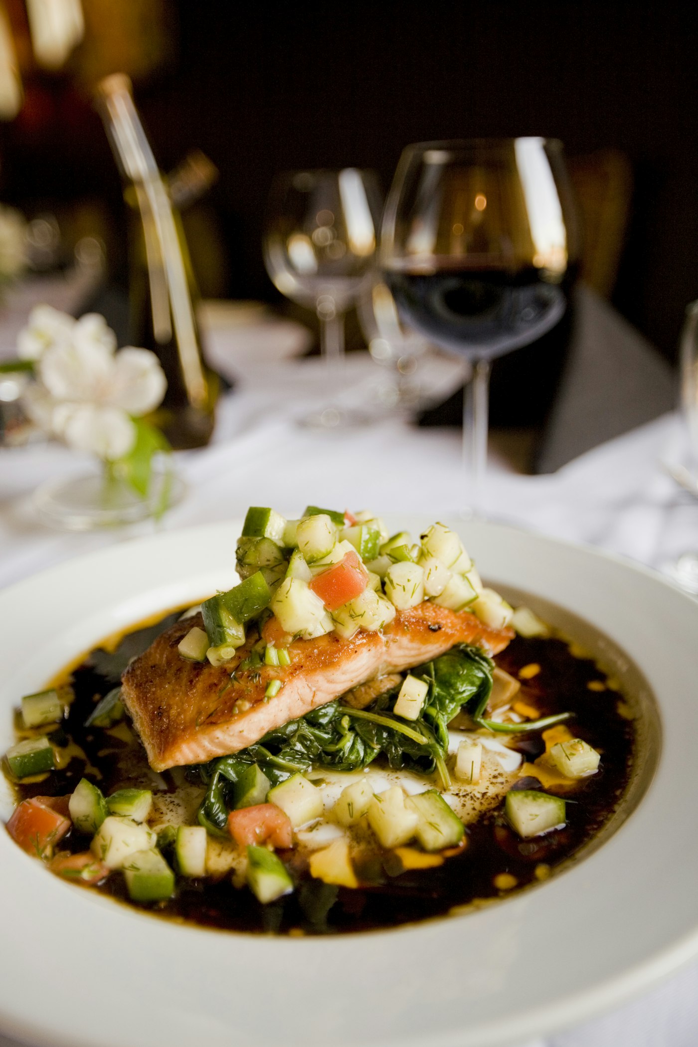 A plated fish dish with a glass of wine